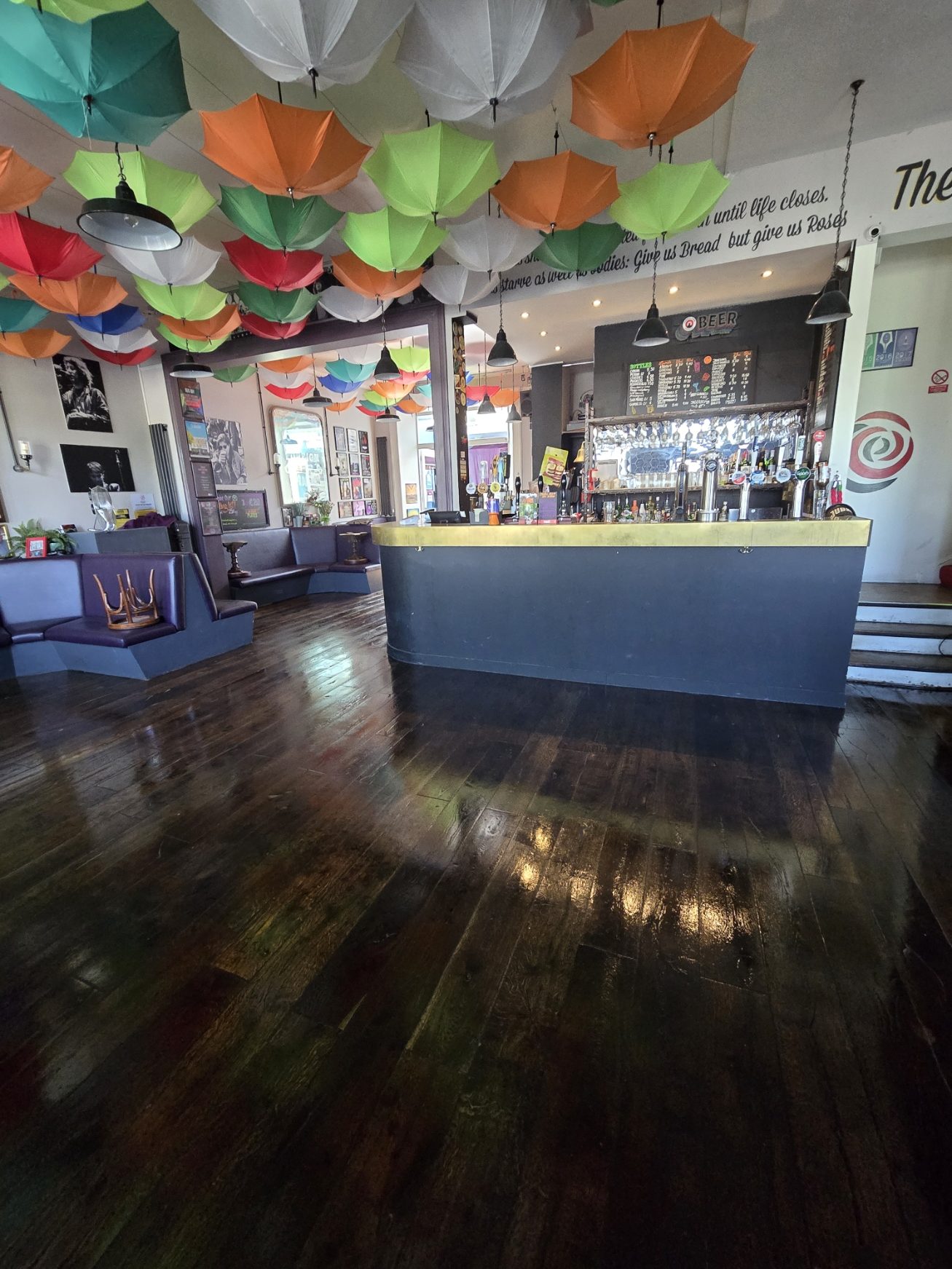 Freshly re-oiled wooden floorboards glowing at The Bread and Roses pub in Clapham, under its colourful umbrella ceiling