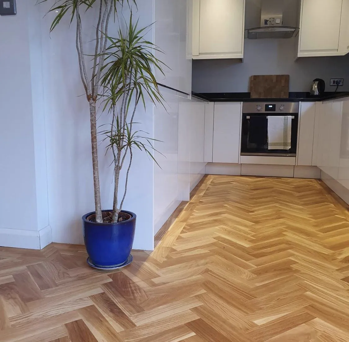 Natural oak herringbone floor fitted through a white kitchen by Howard Naish