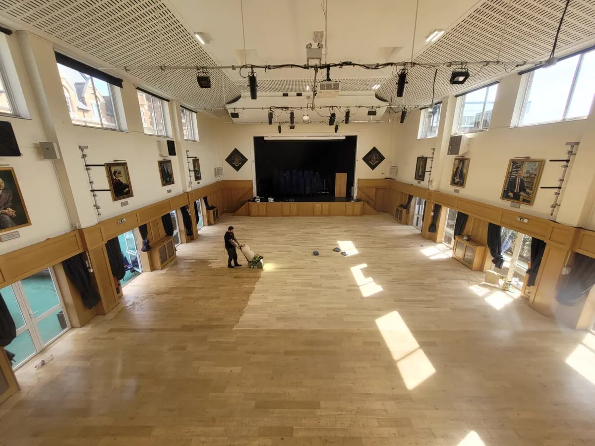 Lagler Hummel belt sander mid-cut across the Emanuel School hall floor