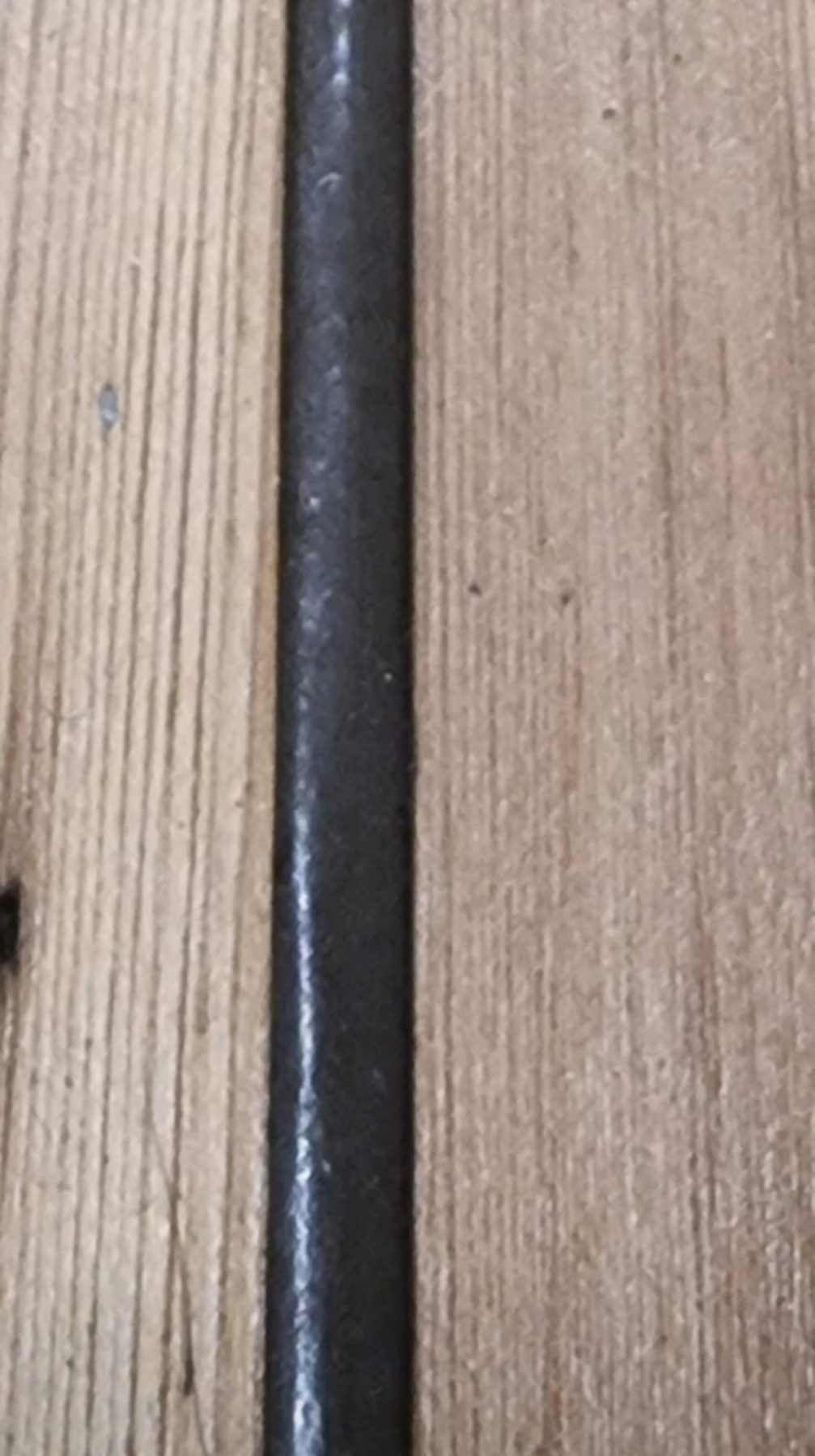 Dark flexible filler in the gap between original pine floorboards