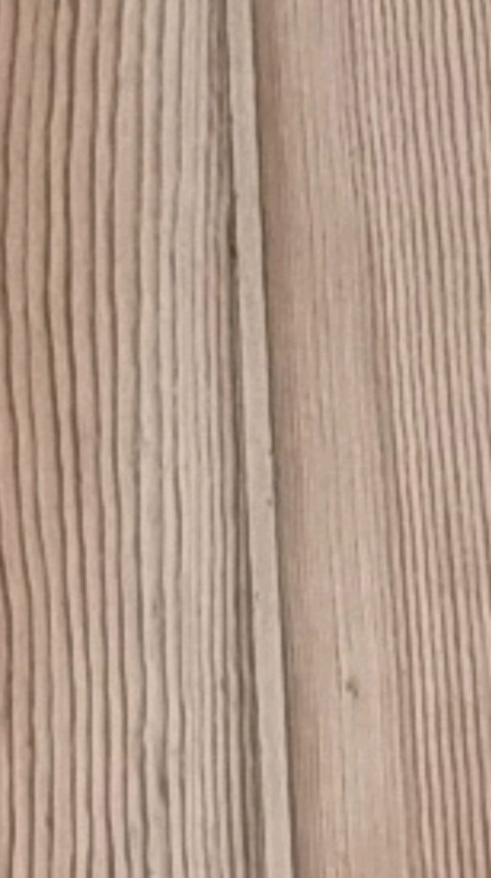 Light-toned flexible filler in the gap between pale pine floorboards