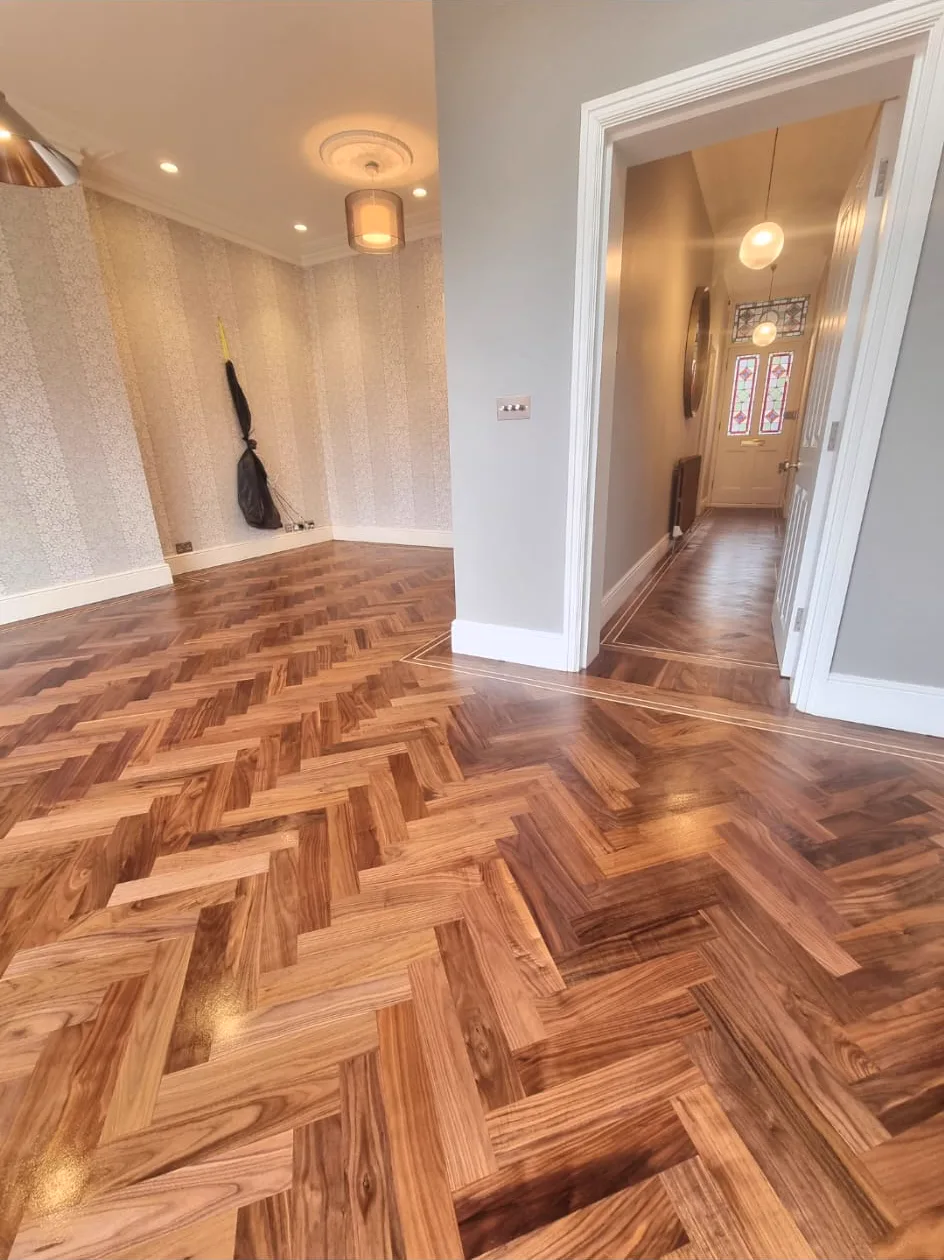 Restored walnut herringbone floor with inlay border flowing from a Fulham SW6 reception into the hallway, sanded and finished by Howard Naish