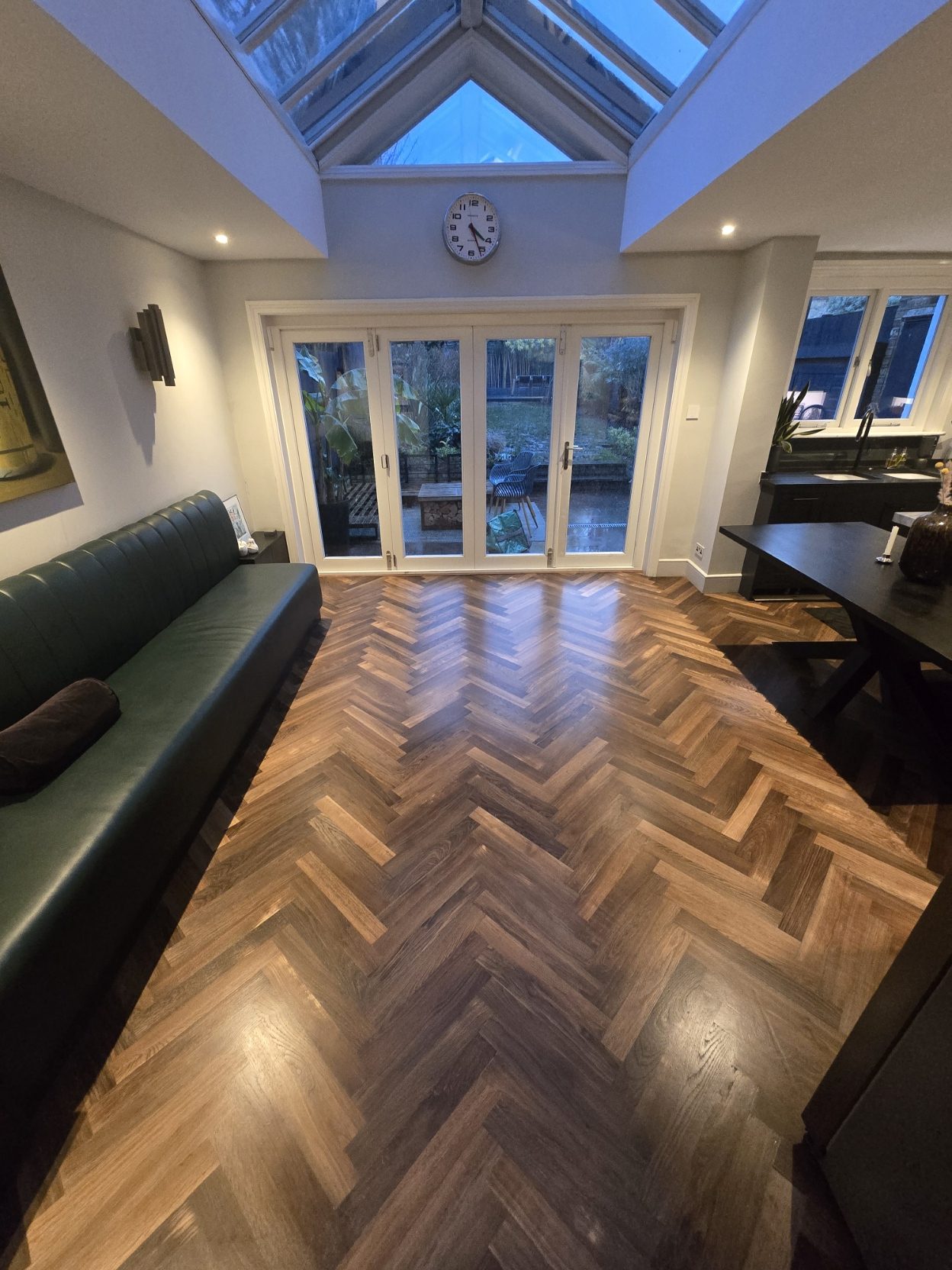 Warm herringbone wood floor glowing in evening light in a London snug