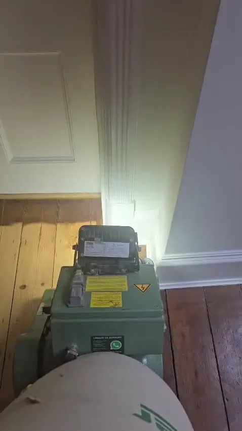 The Lagler Hummel belt sander making its first cut across bare boards, dust pulled straight into the sealed unit
