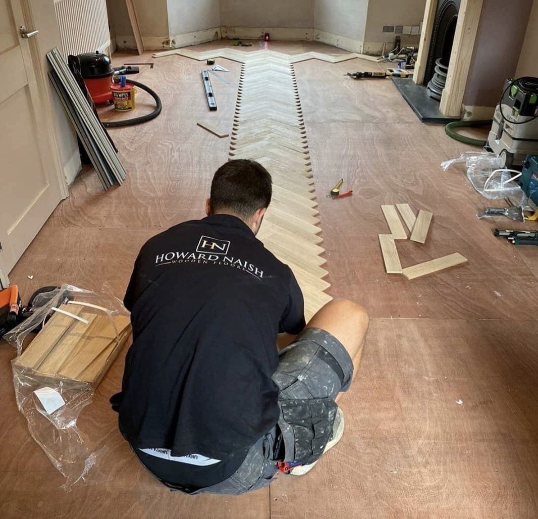 Luke laying an oak herringbone floor in a Howard Naish work shirt