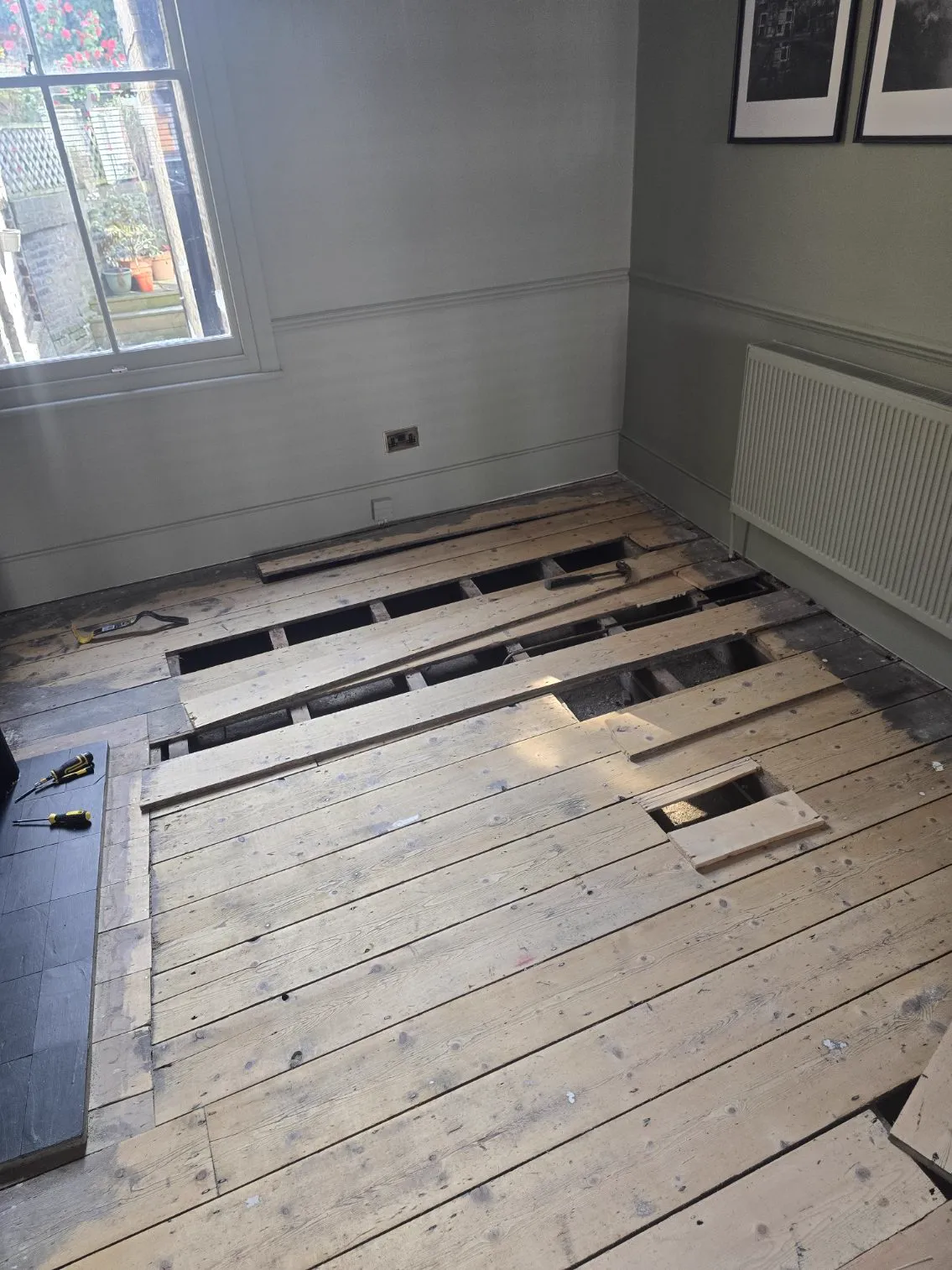 Damaged pine floorboards lifted for replacement, exposing the joists, during a Howard Naish floor restoration