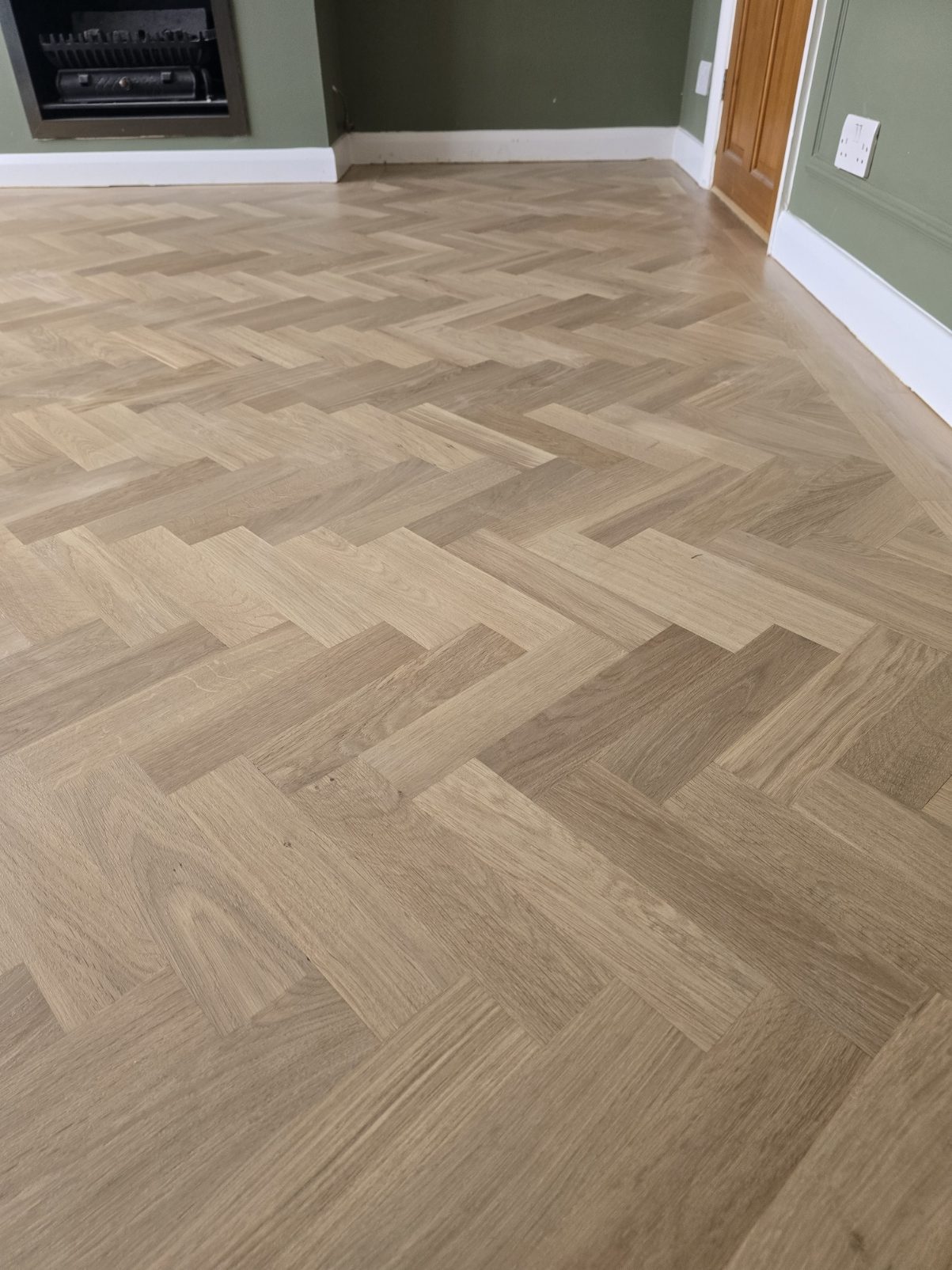 Close-up of prime oak herringbone blocks fitted around a fireplace in a Purley CR8 sitting room