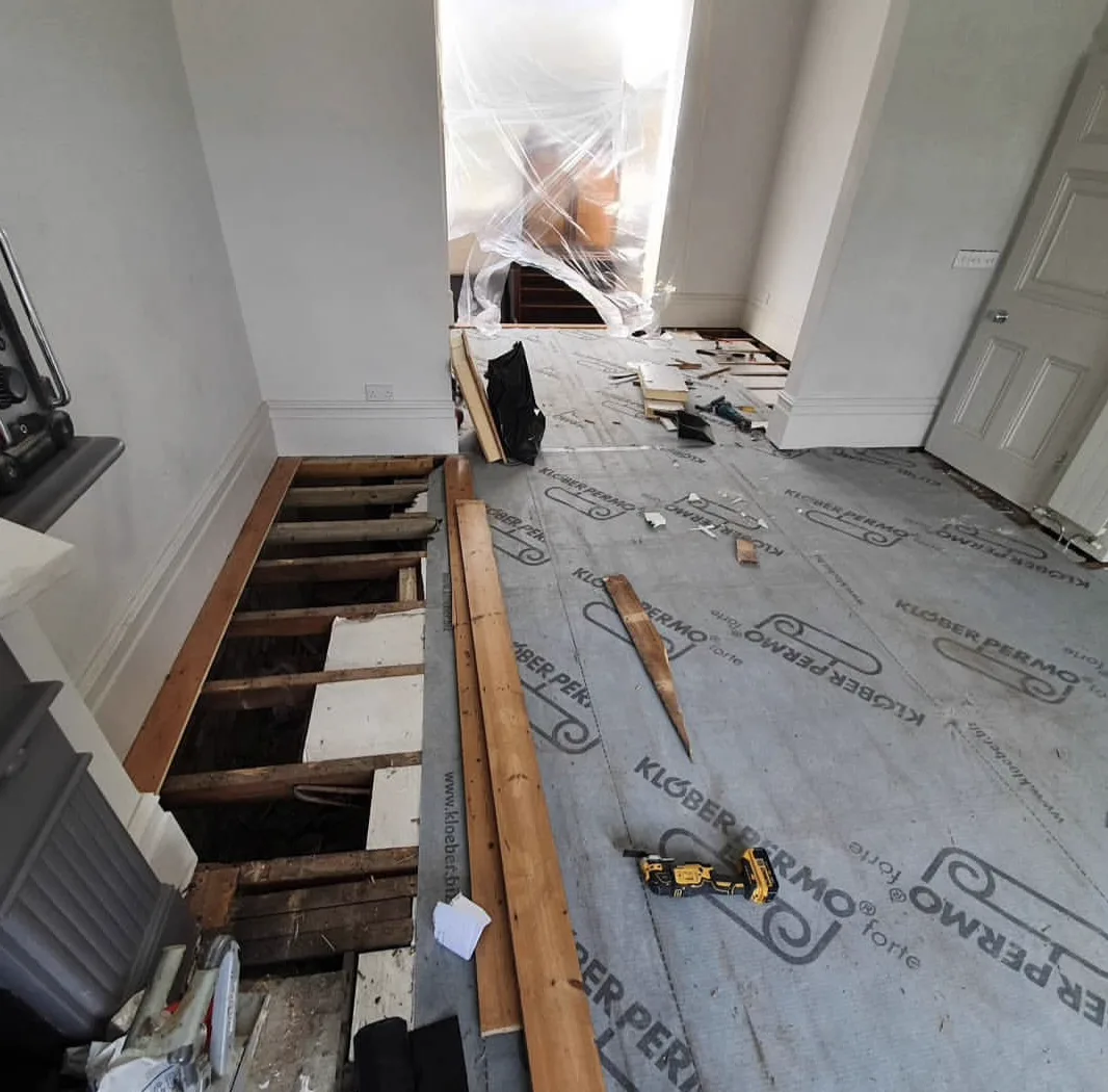 Open joists with grey breathable Klober membrane laid between them during a Tooting SW17 floor renovation by Howard Naish