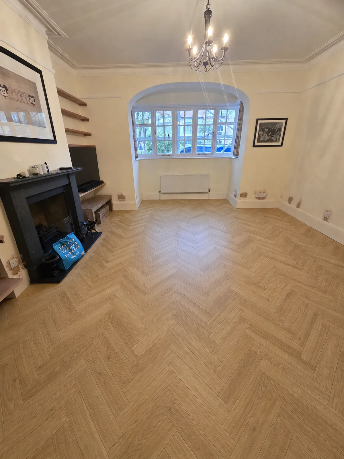 AI visualiser render of the same tired pine room with a Natural oak herringbone floor